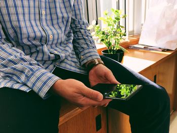 Midsection of woman holding smart phone at home