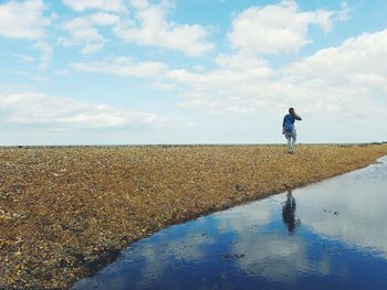 Rear view of woman walking on field against sky