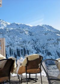 Chairs and tables against snowcapped mountains against clear sky