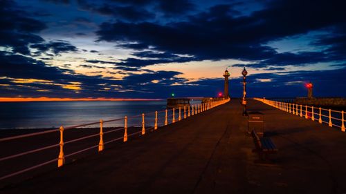 Lighthouse and pier on sea against sky during sunset at yorkshire