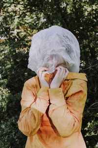 Person wearing textile over face against trees