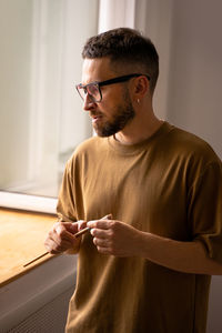 Young man looking away while standing at home