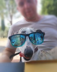 Midsection of person holding sunglasses with dog