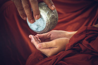 Midsection of monk pouring water on hands