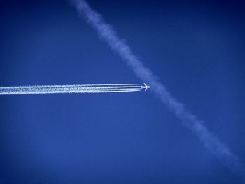 Low angle view of airplane flying against clear blue sky