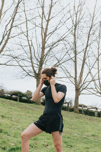 Full length of young woman exercising on field