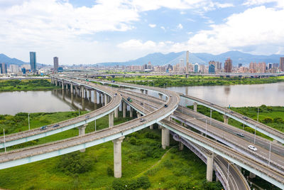 Bridge over river amidst buildings in city against sky