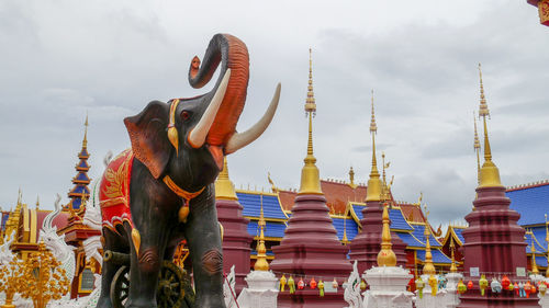 Statue against temple building against sky