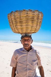 Portrait of smiling man standing at beach against sky