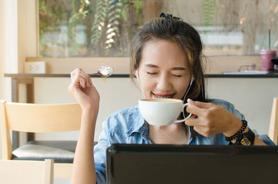 Smiling young woman drinking coffee in cafe