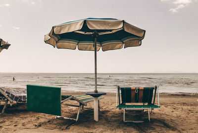 Deck chairs on beach against sky