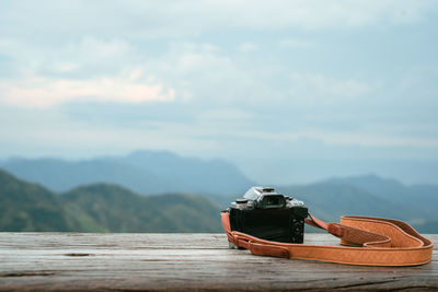 Close-up of camera on wooden plank against landscape