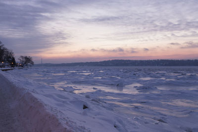 Scenic view of snow covered land against sky during sunset