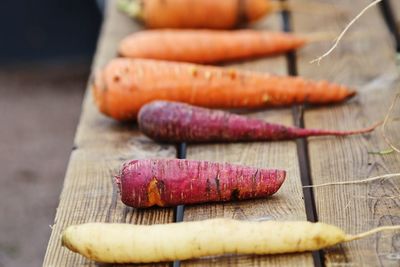 Close-up of different colored carrots laying outdoors  on a wooden table