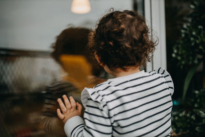 Rear view of child looking  at window