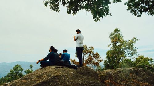 Rear view of men sitting on rock