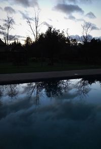 Reflection of silhouette trees in lake against sky