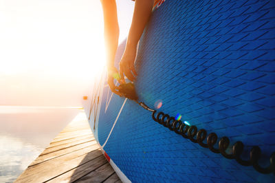 Low section of woman standing on railing against clear sky