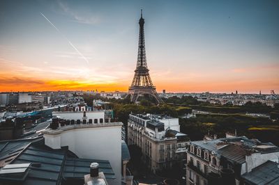 Eiffel tower in city against sky during sunset