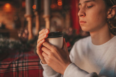 Portrait of candid authentic smiling handsome boy teenager using mobile phone at xmas home interior