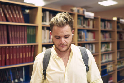 Portrait of a blond boy with headphones entering a library