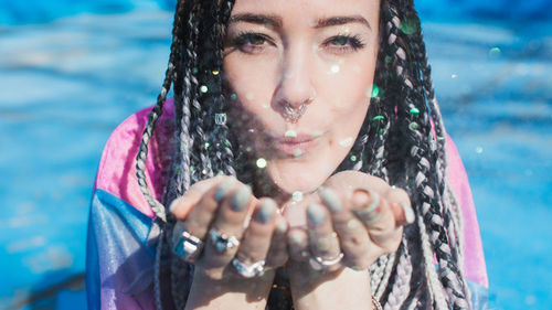 Portrait of smiling young woman blowing glitters