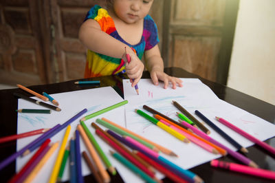 Full length of girl holding pencils on table