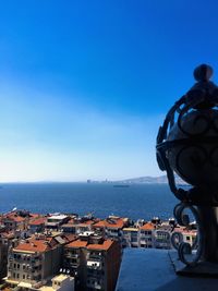 Buildings by sea against blue sky