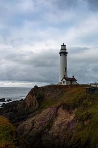 Lighthouse by sea against sky