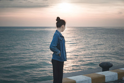 Man looking at sea against sky during sunset