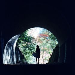 Silhouette woman standing outside tunnel