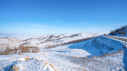 Snow covered landscape against blue sky