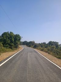 Road by trees against clear sky