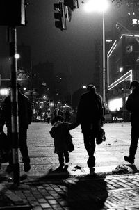 Rear view of people walking on street at night