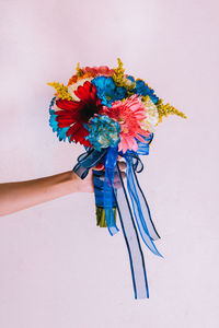 Cropped hand holding flower bouquet against white background