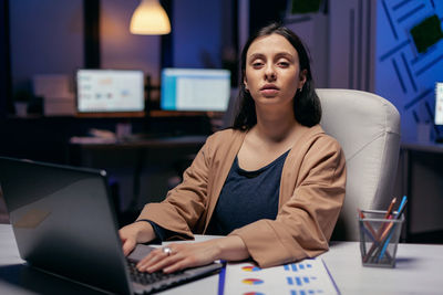 Young woman using mobile phone while sitting on table