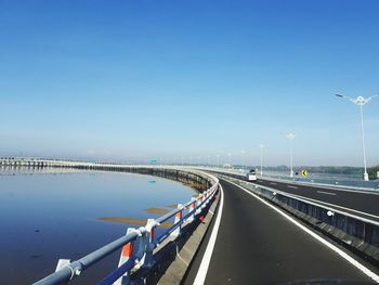 Bridge over road against clear blue sky