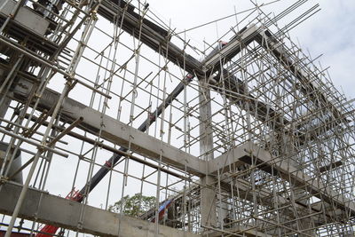 Low angle view of crane in building against sky