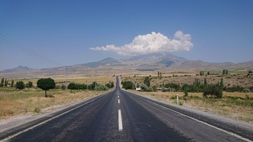 Road leading towards mountains against sky