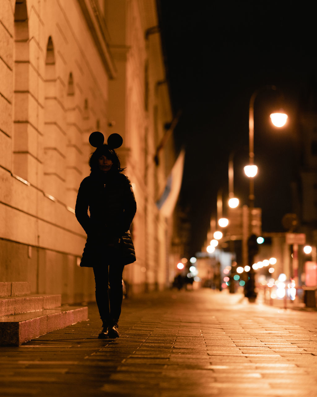 REAR VIEW OF MAN WALKING ON FOOTPATH AT NIGHT