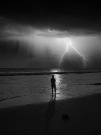 Silhouette of people on beach against sky at night