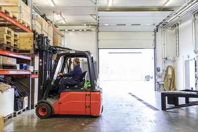 Woman driving forklift truck in warehouse