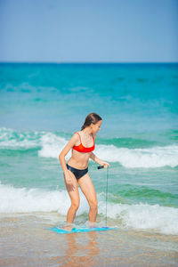 Full length of young woman standing at beach