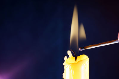 Close-up of lit candle against blue background