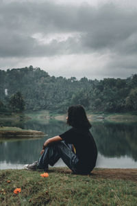 Full length of woman sitting by lake