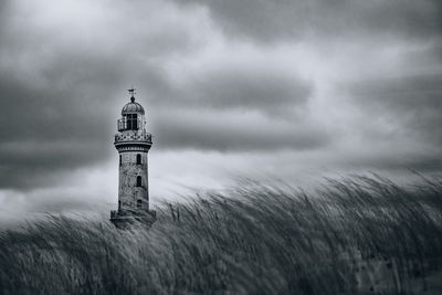 Lighthouse by sea against sky