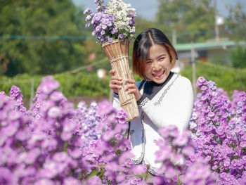 Close-up of woman holding bouquet against purple flowering plants