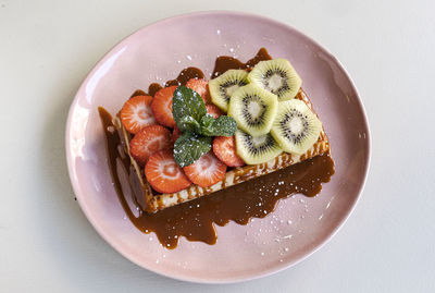 Fantastic waffles with strawberry pieces, kiwis and caramel syrup