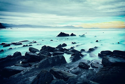 Scenic view of rocks in sea against sky