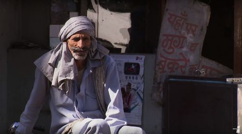 Portrait of mature man sitting by store